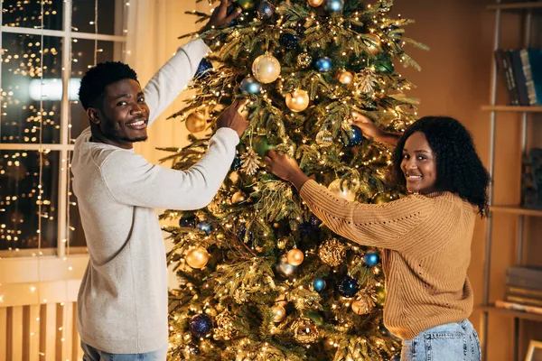 Feliz jovem casal preto decoração bela árvore de Natal juntos em casa — Fotografia de Stock
