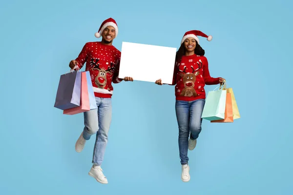 Šťastný africký Američan muž a žena shopaholics ukazuje vánoční nabídku — Stock fotografie