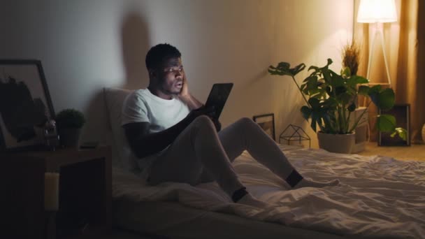 Concepto de estafas móviles. Sorprendido joven afroamericano hombre mirando a la pantalla del teléfono inteligente y tocar la cara en la frustración — Vídeo de stock