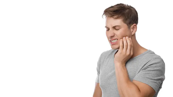 Homem europeu milenar desemparelhado que sofre de dor de dente, pressione mão a mandíbula, mostre descontentamento — Fotografia de Stock