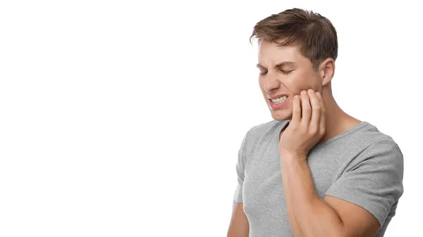 Homme européen millénaire désespéré souffrant de maux de dents, presse la main à la mâchoire, montre du mécontentement — Photo