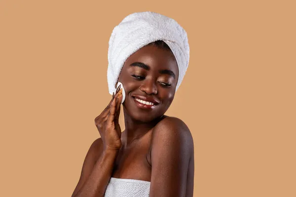 Retrato de mulher negra feliz limpando a pele por almofada de algodão — Fotografia de Stock