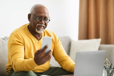 Olgun Afro-Amerikan İşadamı Cep telefonu ve Laptop kullanıyor.