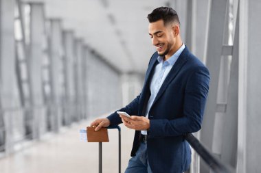 İnternetten Hotel Rezervasyon. Genç Arap İş Adamı Havaalanında Beklerken Akıllı Telefon Kullanıyor