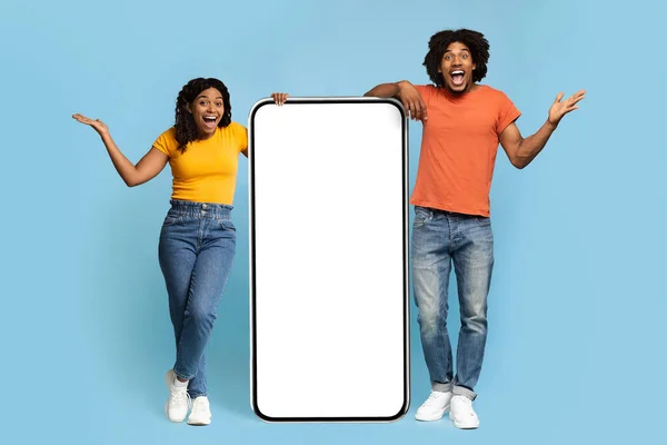Spännande afrikansk amerikansk man och kvinna med stor mobiltelefon, mockup — Stockfoto