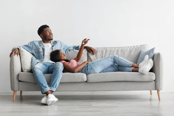 Young black woman switching on air conditioning at home — Stock Photo, Image