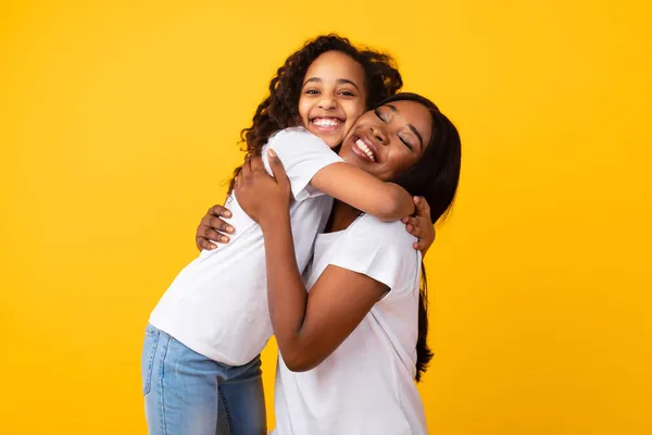 非洲裔美国女孩在工作室拥抱她微笑的妈妈 — 图库照片