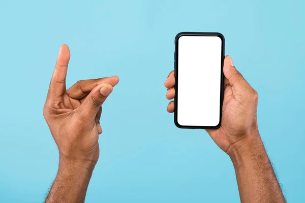 Vedere decupată a tânărului negru care arată smartphone-ul cu ecran alb gol și deține ceva, batjocură — Fotografie, imagine de stoc