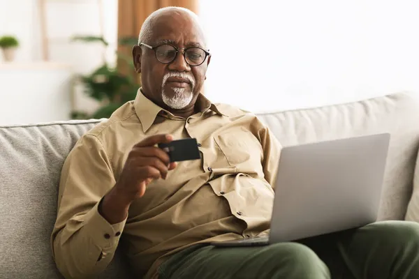 Africano homem compras on-line usando cartão de crédito e laptop interior — Fotografia de Stock