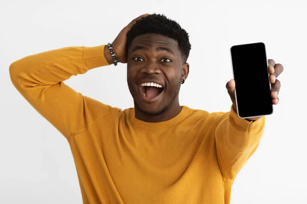 Hombre negro impactado mostrando teléfono inteligente con pantalla vacía — Foto de Stock