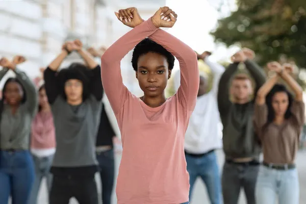 Афро-американская женщина, направляет многонациональную группу активистов, скрещивает кулаки — стоковое фото