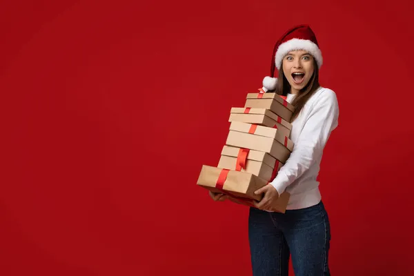 Sorpresa de Navidad. Mujer emocionada en Santa Sombrero celebración pila de cajas de regalo — Foto de Stock