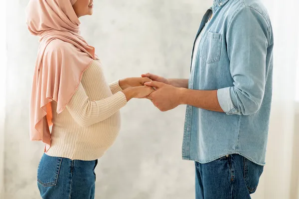 Zijaanzicht van liefdevolle zwangere moslim paar hand in hand, Arabische echtgenoten verwacht voor baby, gewas, close-up — Stockfoto