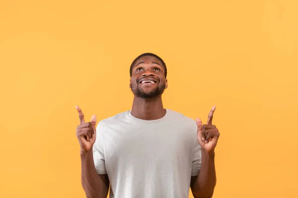 Kijk hier. Positieve zwarte man wijst naar vrije ruimte boven zijn hoofd, toont lege plek voor uw advertentie — Stockfoto