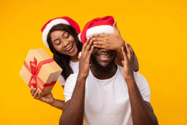 Novia negra Novio sorprendente con regalo de Navidad sobre fondo amarillo —  Fotos de Stock