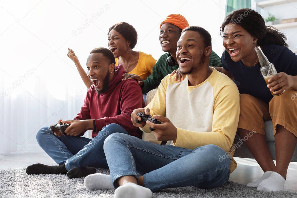 Cheerful african american friends playing video games at home