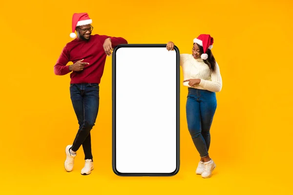 Afrikaans paar dragen Santa hoeden wijzende vingers aan de telefoon, Studio — Stockfoto