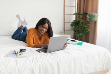 Mutlu Black Freelancer Kadını Laptop kullanıyor Yatak odasında çalışıyor