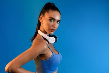 Kulaklıklı Atletik Kadın Mavi Stüdyo Arkaplanda Poz Veriyor