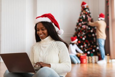 Mutlu siyah bayan Xmas arifesinde dizüstü bilgisayar kullanıyor.