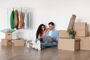 Mutlu milenyum çifti taşındıktan sonra dizüstü bilgisayar kullanıyor.