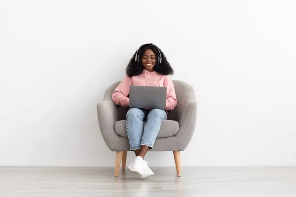 Sorridente signora afro-americana guardando film online, utilizzando il computer portatile — Foto Stock