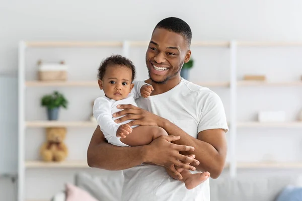 親の概念。陽気なアフリカ系アメリカ人の男の肖像彼の幼児を保持 — ストック写真