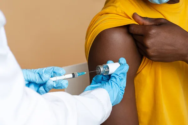 Läkare i blå handskar som tar vaccindosen från injektionsflaskan med spruta — Stockfoto