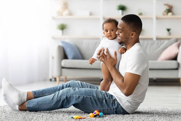 Więź z dzieckiem. czarny człowiek bawiąc się z jego dziecko w domu — Zdjęcie stockowe