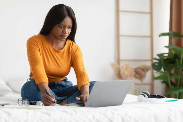 ベッドルームで働くラップトップブラウジングインターネットを使用して深刻な黒の女性 — ストック写真