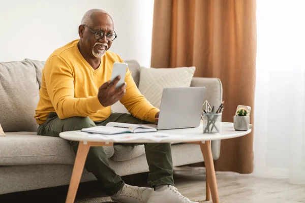Homem Africano Americano Sênior Usando Smartphone e Laptop Em Casa — Fotografia de Stock