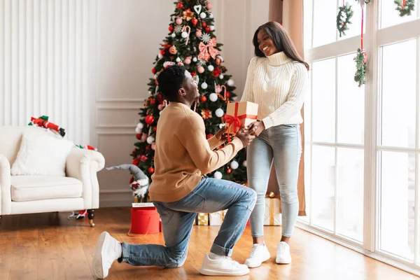 Portret van een gelukkig zwart gezin dat Kerstmis viert, man die cadeautjes geeft — Stockfoto