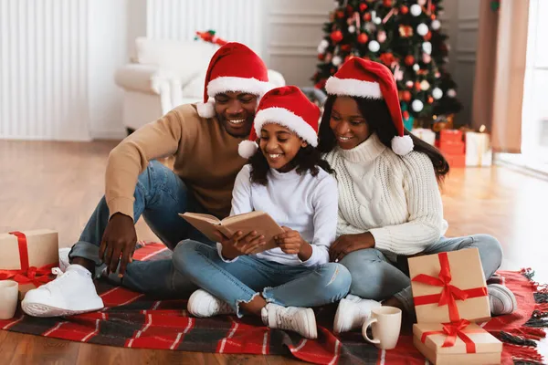 Noel Baba 'daki mutlu siyah ailenin portresi kitap okuyor.