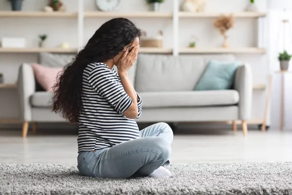 Плаче вагітна жінка, яка відчуває себе внизу, перебуваючи сама вдома — стокове фото