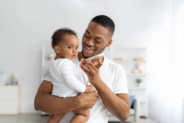 Nowoczesne technologie i dzieci. Ojciec trzymający niemowlę i mówiący przez głośnik — Zdjęcie stockowe