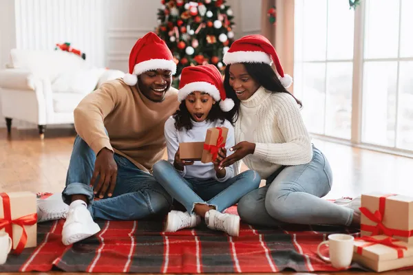 Överraskad svart flicka firar jul inslagning presentförpackning — Stockfoto