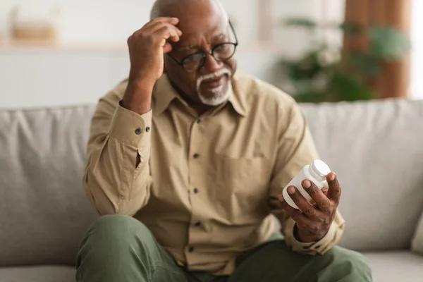 Homem Africano Americano Sênior Segurando pílulas médicas Instrução de leitura Indoor — Fotografia de Stock