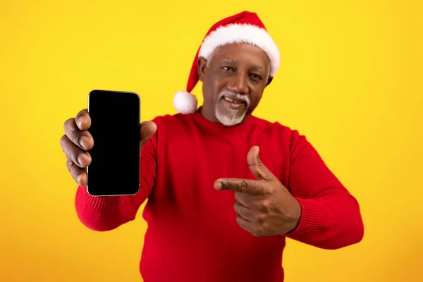 Oferta de Navidad. Feliz hombre negro senior con sombrero de Santa, demostrando pantalla de teléfono inteligente en blanco con maqueta — Foto de Stock