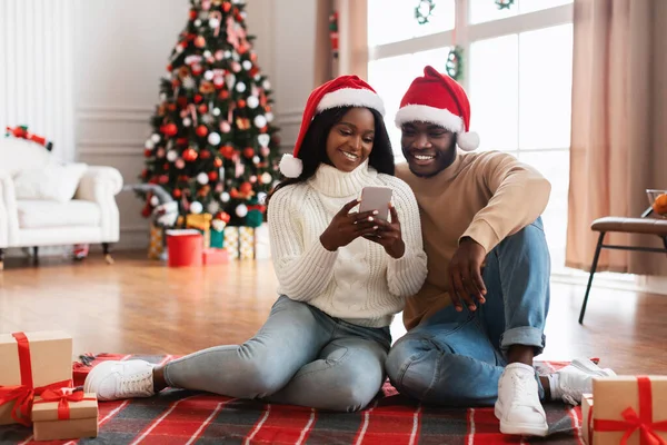 Glad festlig svart familj med mobiltelefon välja gåvor på Xmas — Stockfoto