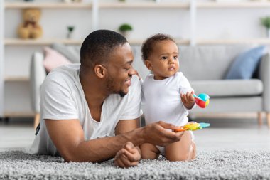 Mutlu Afrikalı Amerikalı baba evde küçük çocukla oynuyor.