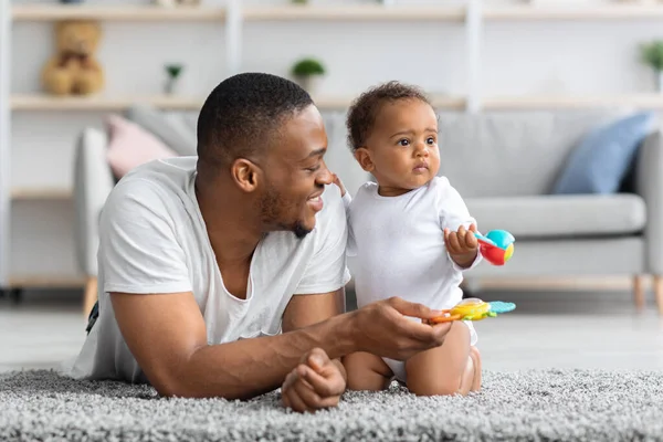 Szczęśliwy Afroamerykanin tata bawiący się z małym maluchem w domu — Zdjęcie stockowe