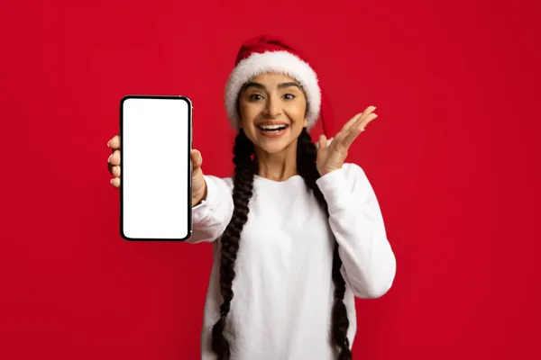 Offerta fantastica. Donna araba eccitata che indossa il cappello di Babbo Natale che dimostra smartphone vuoto — Foto Stock