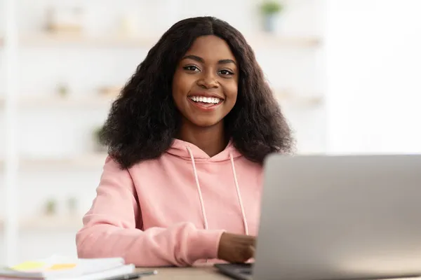 Sonriente freelancer mujer negra trabajando desde casa, usando un cuaderno — Foto de Stock