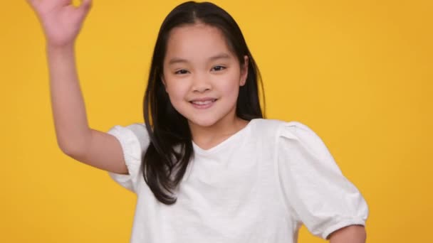 Утверждение и удовольствие. Счастливая уверенная в себе девочка-азиатка, показывающая нормальный жест и улыбающаяся в камеру — стоковое видео