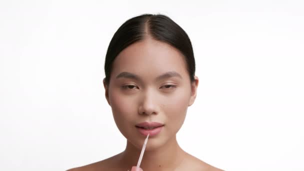 Koreanerin trägt Lippenstift-Lächeln-Make-up auf weißem Hintergrund auf — Stockvideo