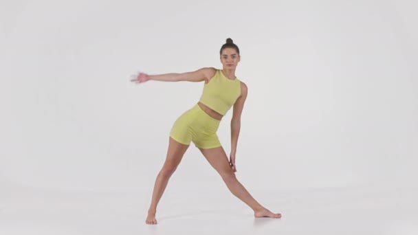 Junge aktive, sportliche Frau in gelbem Sportanzug, die Trikonasana-Pose macht, Yoga praktiziert, Ganzkörperaufnahme — Stockvideo