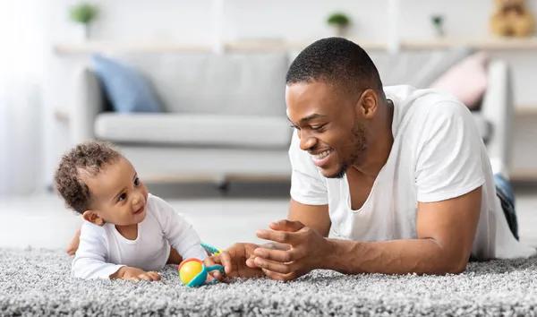 Father-infant bonding. Happy young black dad playing with baby son at home — Stock Photo, Image