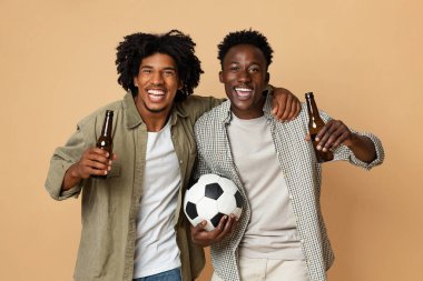 Futbol fanatikleri. İki Neşeli Zenci Futbol Topu Tutuyor ve Bira İçiyor