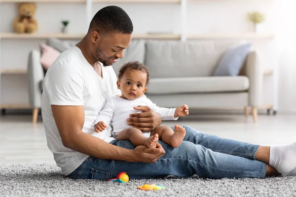 Feliz licença de paternidade. Jovem preto pai ligação com bebê infantil em casa — Fotografia de Stock