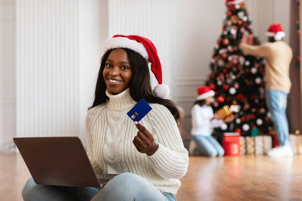 クリスマスオンラインショッピング。クレジットカードを示すラップトップを使用して笑顔の女性 — ストック写真